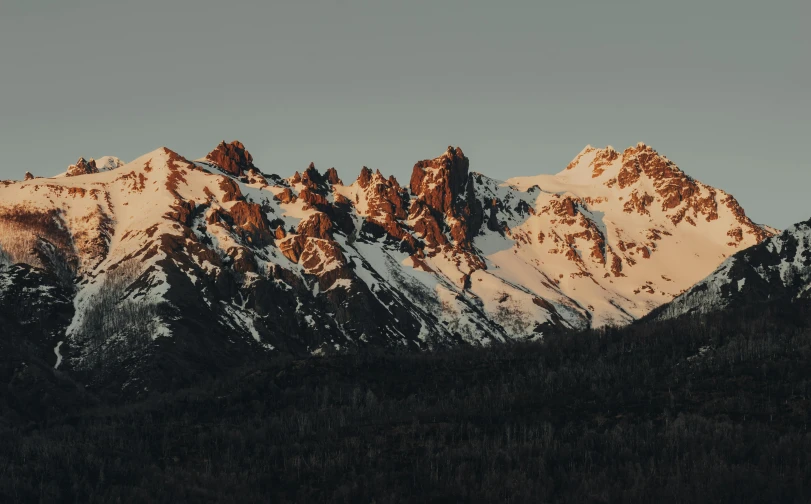 a large mountain covered in snow next to a forest, unsplash contest winner, minimalism, snowy craggy sharp mountains, late afternoon light, obsidian towers in the distance, brown