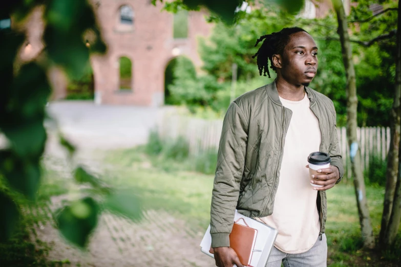 a man with dreadlocks holding a cup of coffee, by Julian Allen, trending on unsplash, walking at the garden, post graduate, black teenage boy, looking serious