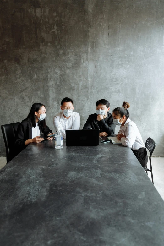 a group of people sitting around a table with a laptop, wearing a mask, slightly minimal, slick design, asia