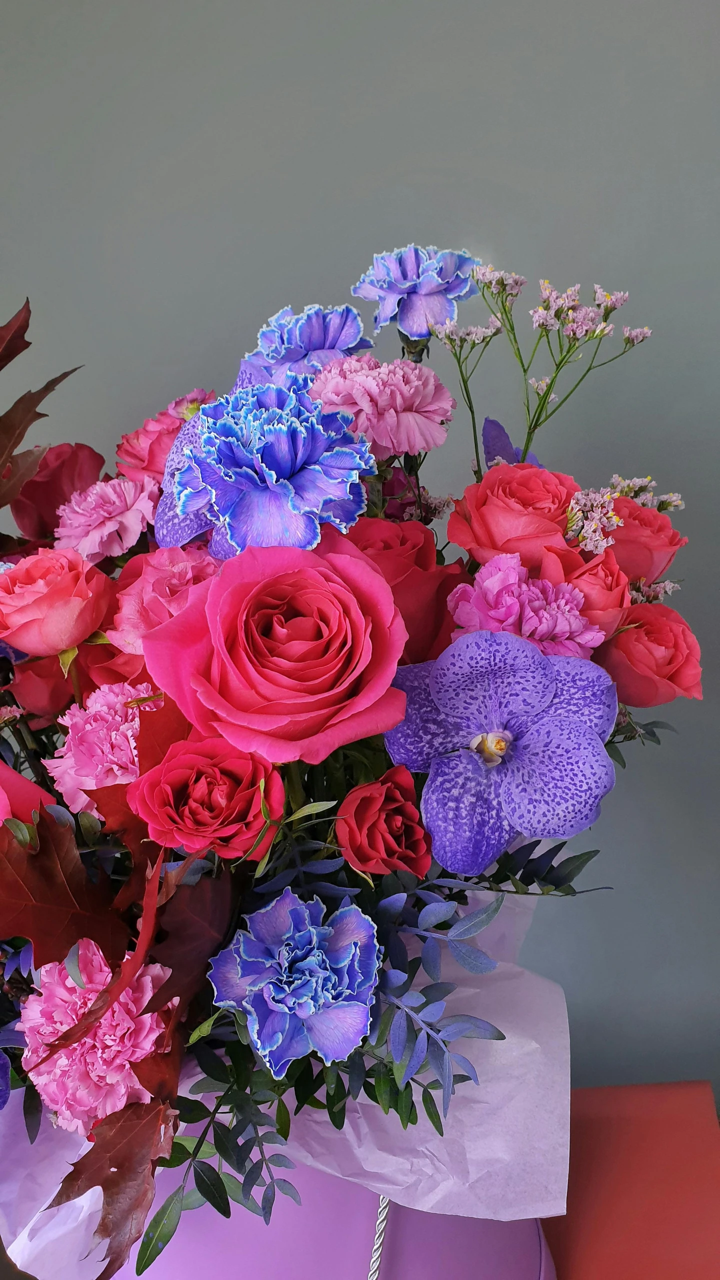 a bouquet of flowers in a box on a table, purple and pink and blue neons, purple and scarlet colours, up close shot, large tall