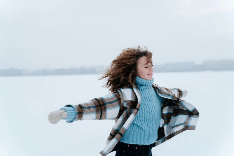 a woman riding a snowboard across a snow covered field, an album cover, pexels contest winner, windy floating hair!!, carefree, blue, arms out