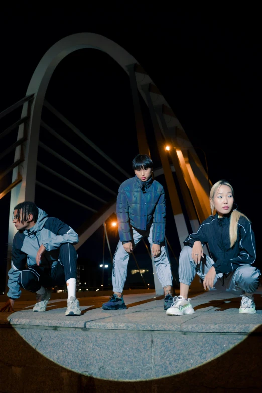 a group of people standing on top of a bridge, an album cover, inspired by Gang Hui-an, lyco art, 2 techwear women, wearing track and field suit, confident pose, photo taken at night