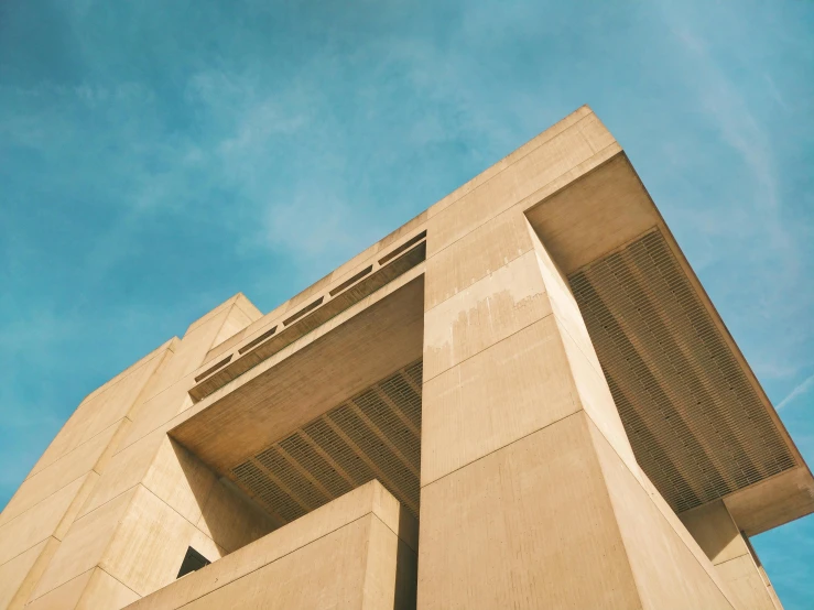 a tall building with a blue sky in the background, inspired by Ricardo Bofill, pexels contest winner, brutalism, sand - colored walls, cairo, museum of art, 3d architecture