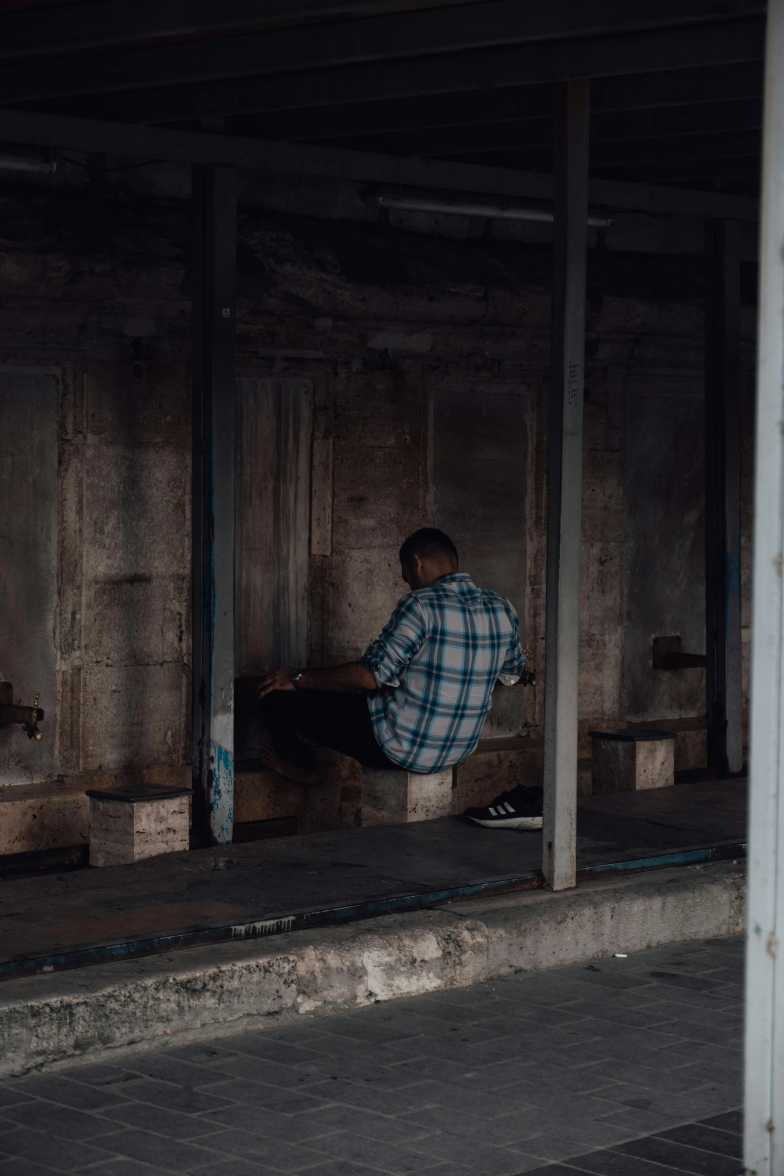 a man sitting on a bench at a train station, a picture, by Elsa Bleda, trending on unsplash, graffiti, praying with tobacco, abandoned building, they are crouching, siting on a toilet