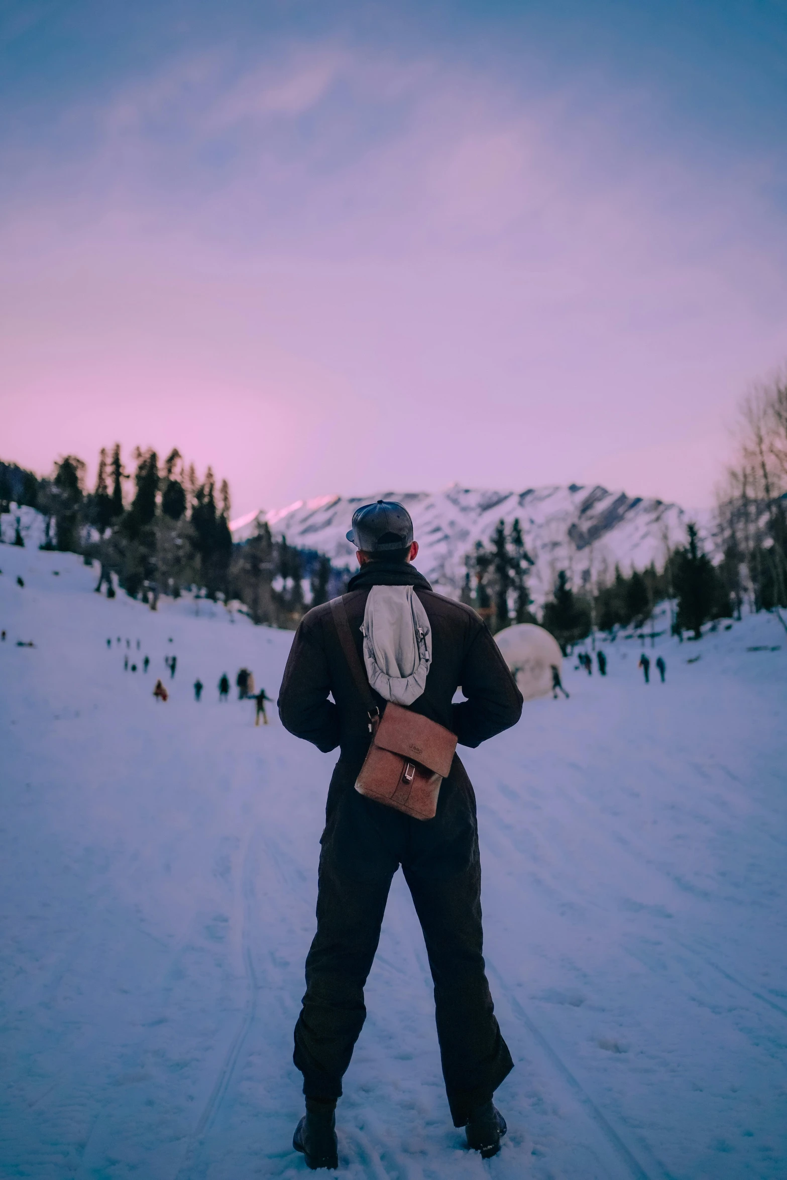 a man standing on top of a snow covered slope, a picture, trending on unsplash, carrying a saddle bag, early evening, crowd, whistler