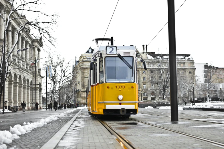 a yellow trolley traveling down a snow covered street, inspired by István Regős, pexels contest winner, viennese actionism, square, grey, tie-dye, exterior