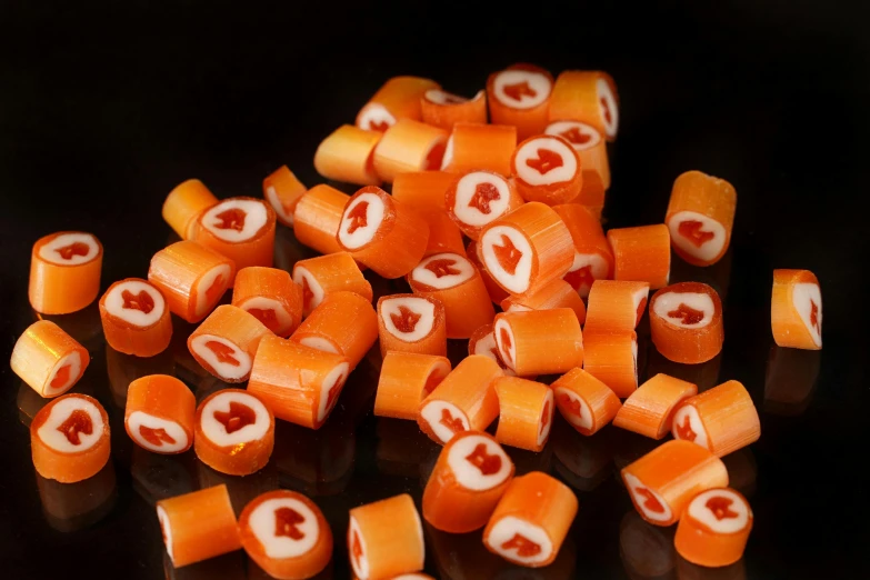 a pile of sliced carrots sitting on top of a table, inspired by Hermann Rüdisühli, reddit, hurufiyya, made of candy and lollypops, with a black background, made of swiss cheese wheels, jelly - like texture