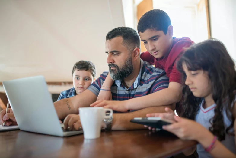 a group of children sitting around a man on a laptop, pexels, middle eastern, te pae, parents watching, thumbnail