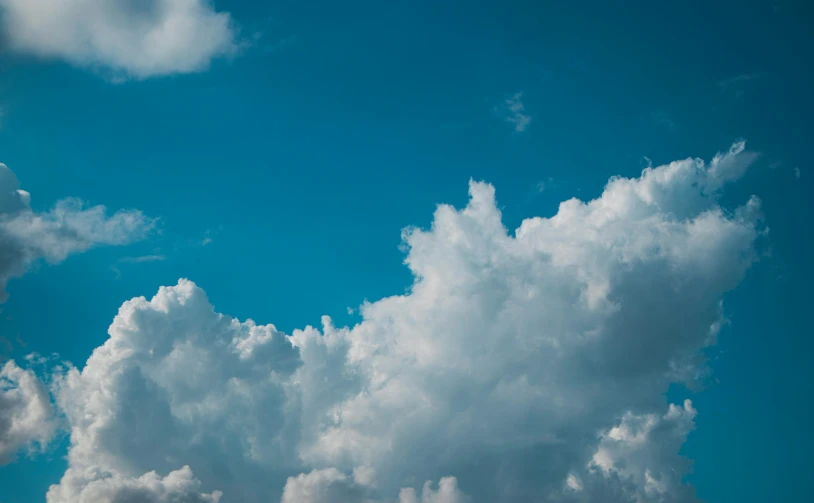 a plane flying through a cloudy blue sky, pexels contest winner, minimalism, towering cumulonimbus clouds, looking at the sky, uploaded, bright blue sky