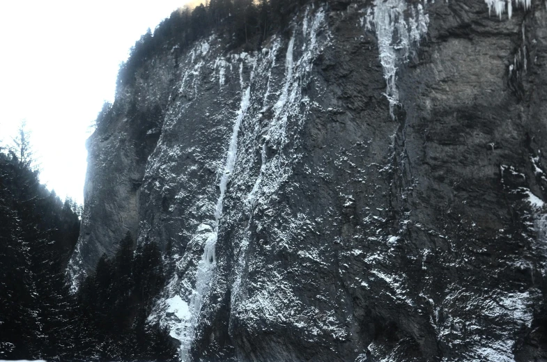 a group of people standing in front of a waterfall, an album cover, by Johannes Voss, pexels contest winner, hurufiyya, extremely detailed rocky crag, ground covered with snow, view from the street, taken on iphone 14 pro