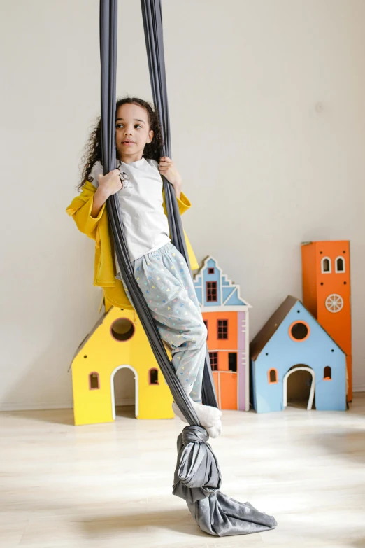 a little girl sitting on a swing in a room, inspired by The Family Circus, pexels contest winner, arabesque, grey, posable pvc, official product photo, parachutes