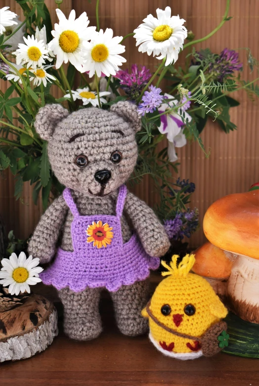 a teddy bear sitting next to a bunch of flowers, inspired by Beatrix Potter, crochet skin, with chicks, dark grey, summer meadow