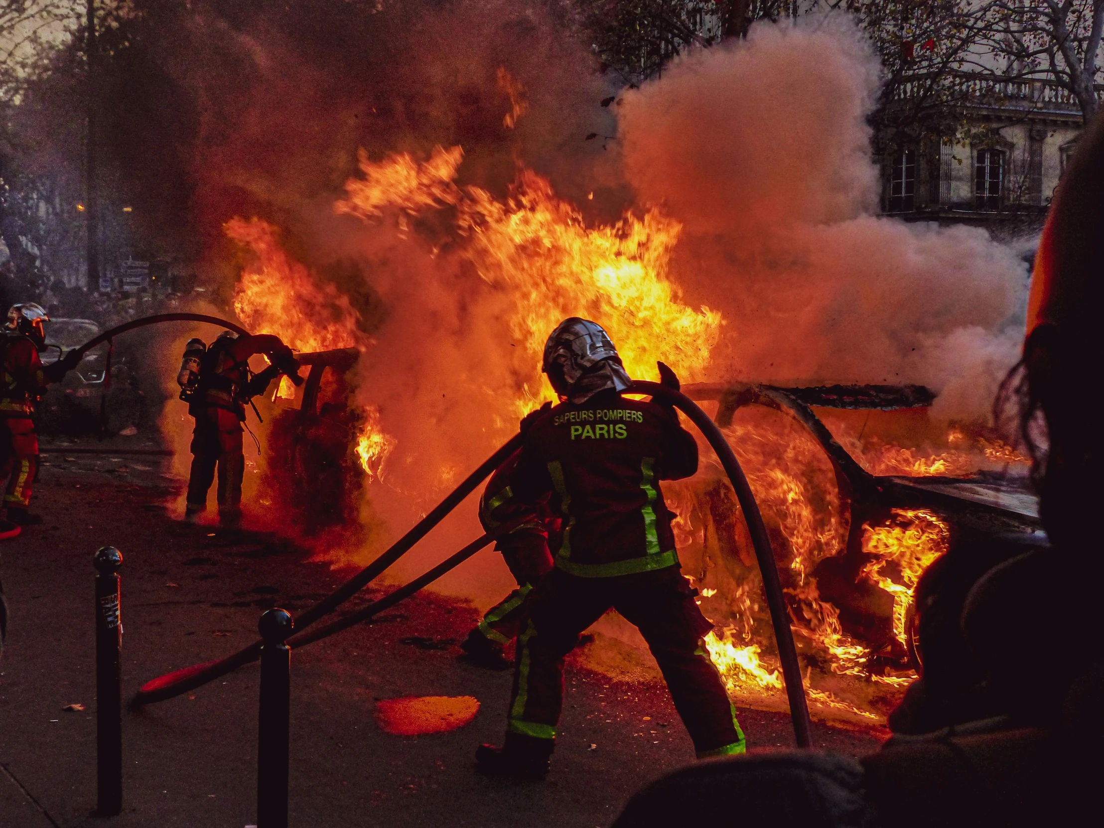 a group of firefighters standing in front of a fire, pexels contest winner, auto-destructive art, in paris, 🦩🪐🐞👩🏻🦳, police officers under heavy fire, car on fire