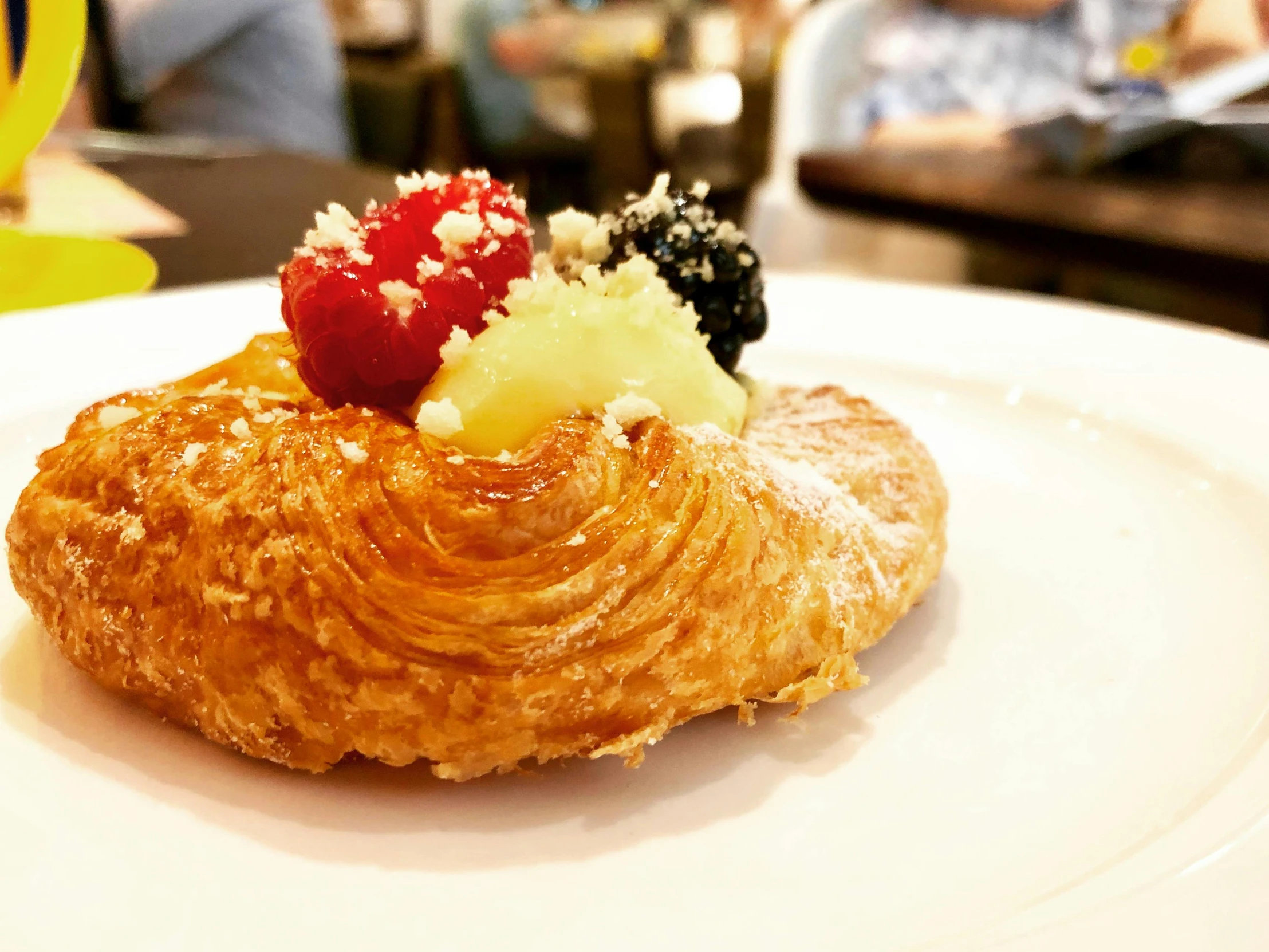 a white plate topped with a pastry covered in fruit, inspired by Barthélemy Menn, unsplash, hurufiyya, full round face!, crispy, warm, inside a grand