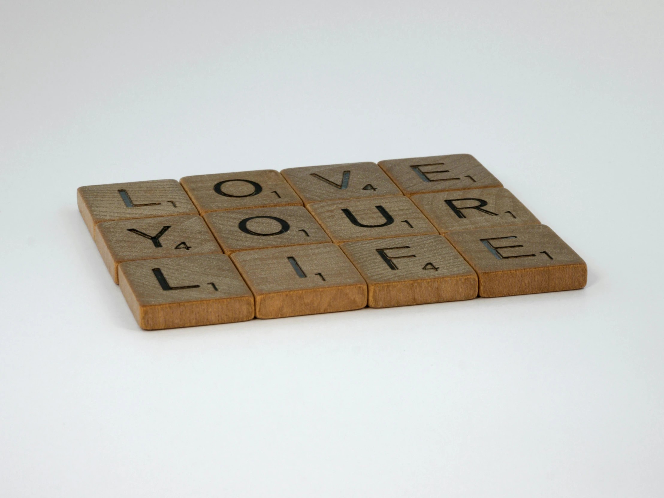 a scrabble with the words love your life written on it, inspired by Ian Hamilton Finlay, letterism, brown resin, thumbnail, 1950s, - 12p