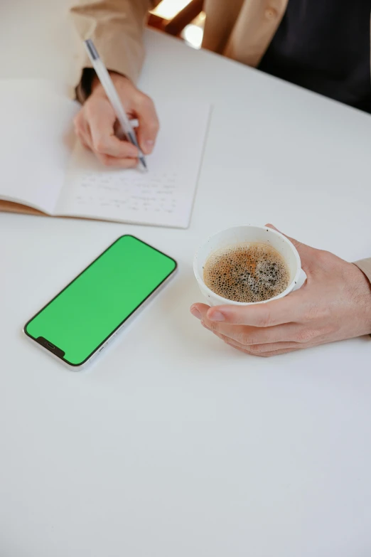 a person sitting at a table with a cup of coffee and a cell phone, skin painted with green, no - text no - logo, whiteboards, detailed product image