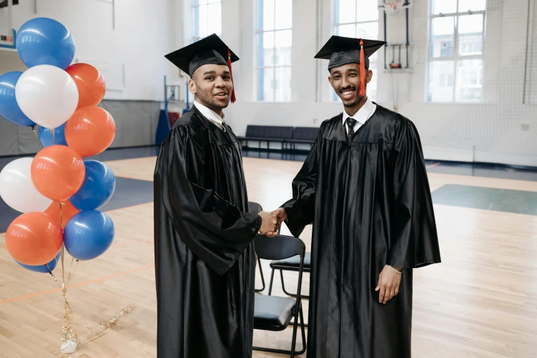 two men in graduation gowns shaking hands, a portrait, by Everett Warner, pexels contest winner, essence, in the high school gym, promo image, ( ( theatrical ) )