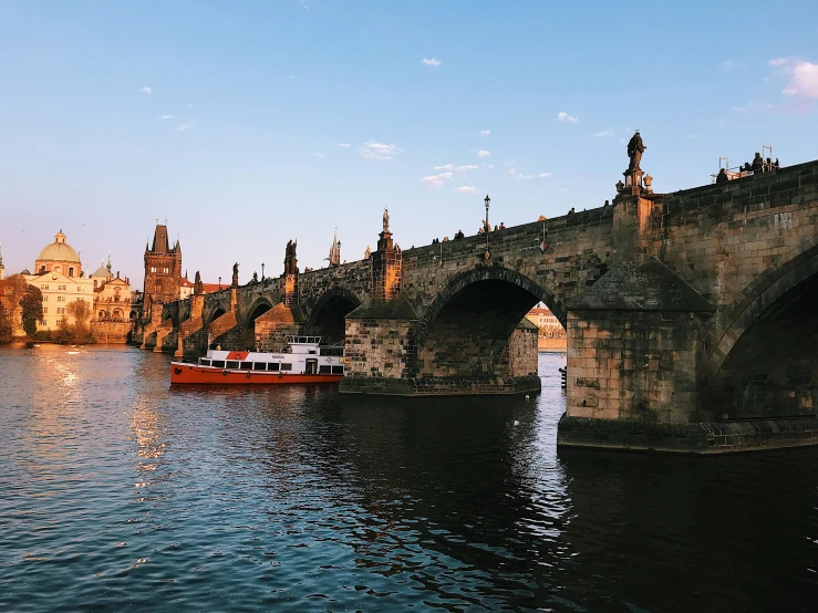 a boat traveling down a river next to a bridge, by Tom Wänerstrand, pexels contest winner, art nouveau, prague, 🦩🪐🐞👩🏻🦳, olafur eliasson, a cozy