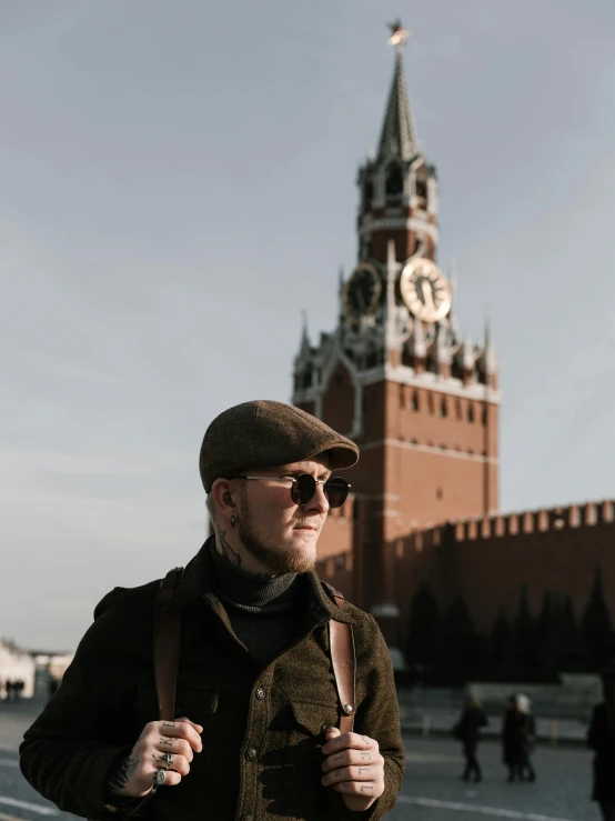 a man standing in front of a clock tower, inspired by Vasily Surikov, pexels contest winner, wearing sunglasses and a cap, profile image, red square, avatar image