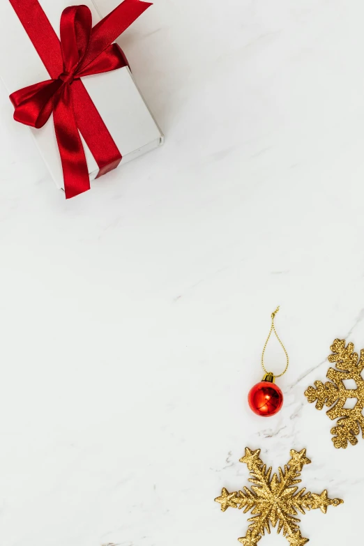 a gift box sitting on top of a snow covered ground, gold adornments, set against a white background, promo image, red adornments