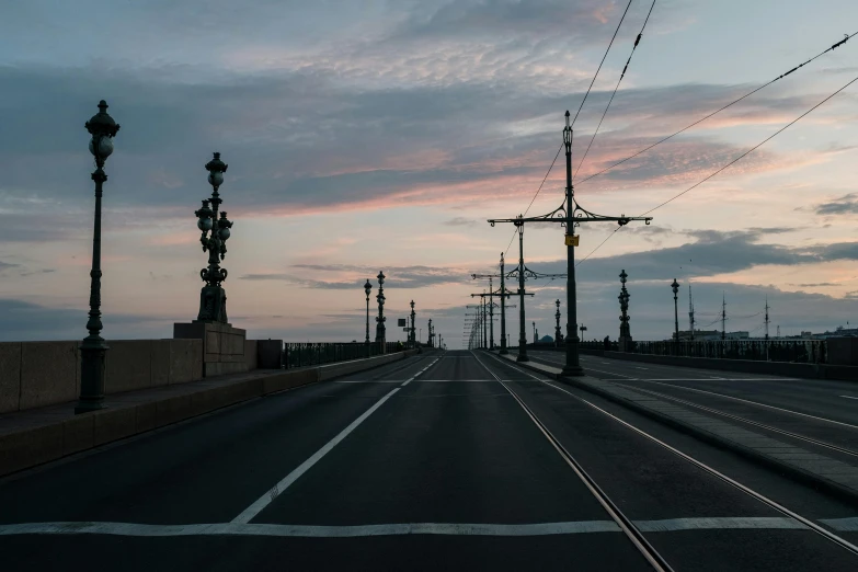 a street lined with street lights next to a bridge, pexels contest winner, postminimalism, peter the great, at dawn, caspar friedrich, street tram