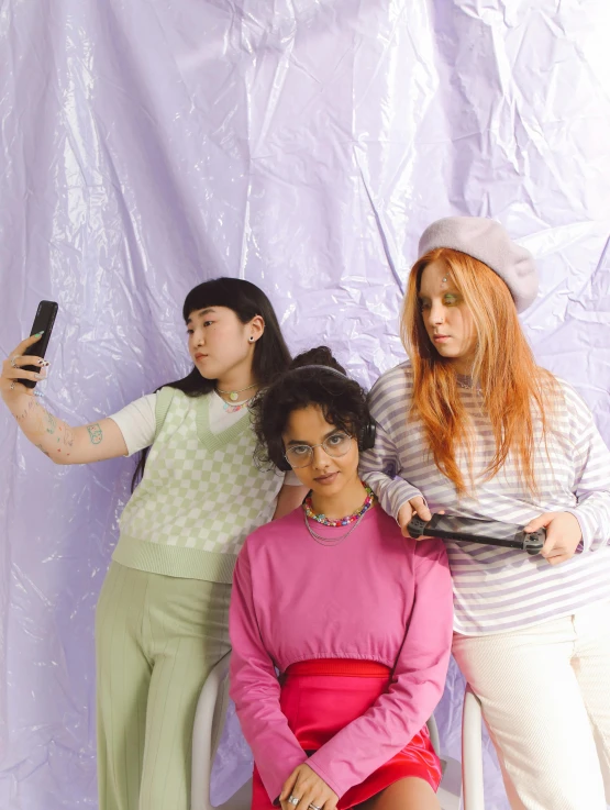 a group of women sitting on top of a white chair, trending on pexels, feminist art, pastel goth aesthetic, hold up smartphone, wearing a purple sweatsuit, three women