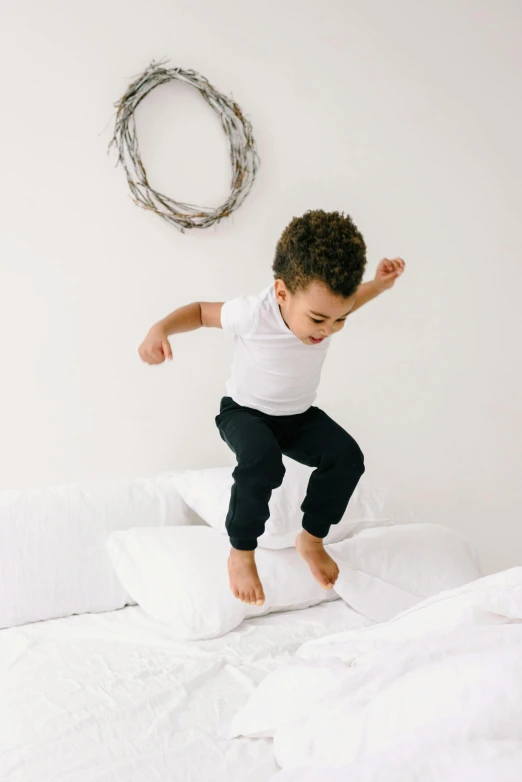 a young boy jumping on top of a bed, inspired by Myles Birket Foster, pexels contest winner, arabesque, collection product, white, black, organic detail