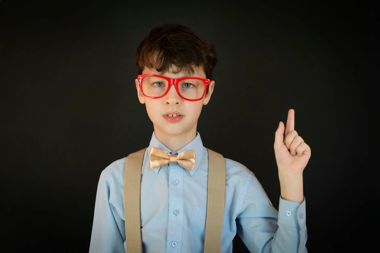 a young boy wearing red glasses and a bow tie, by Matthias Stom, pexels, incoherents, pointing, red and blue neon, square rimmed glasses, high school