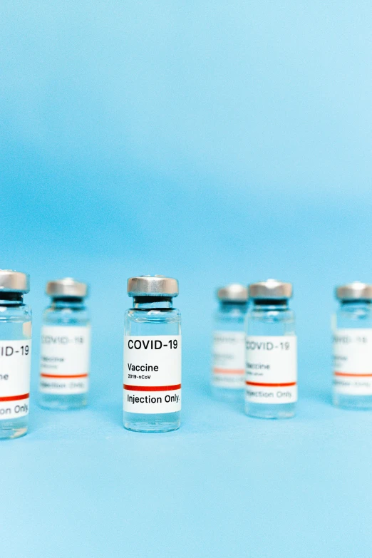 a row of vials filled with vaccines on a blue background, a picture, by Jeanna bauck, shutterstock, instagram post, covid, ships, profile pic