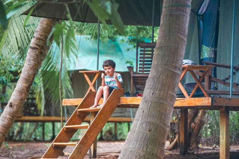 a young boy sitting on top of a wooden slide, by Sebastian Vrancx, pexels contest winner, sri lanka, glamping, sitting on a table, listing image