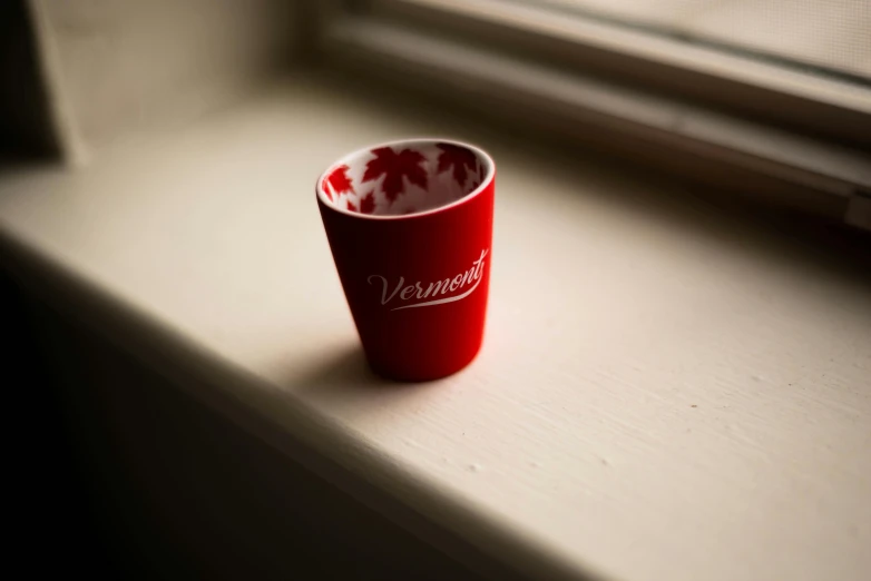 a red cup sitting on top of a window sill, unsplash, photorealism, engraved, mini model, new hampshire, leafs