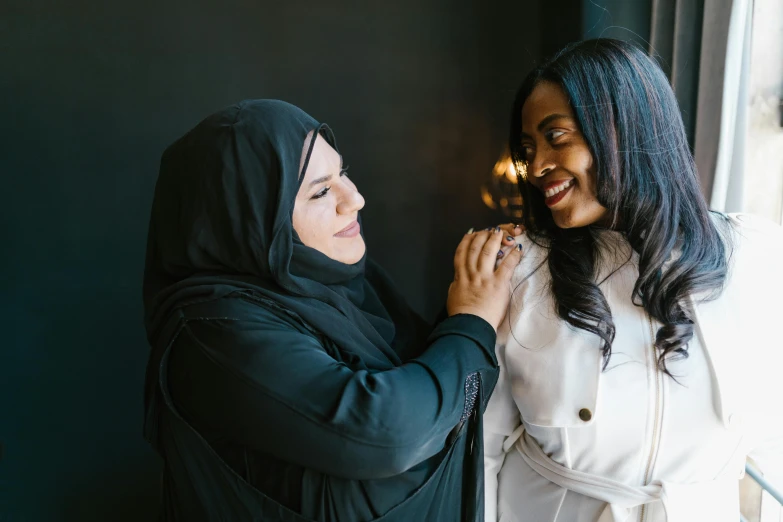 a couple of women standing next to each other, by Meredith Dillman, pexels contest winner, hurufiyya, wearing robes and neckties, zenra taliyah, smiling at each other, holding an epée