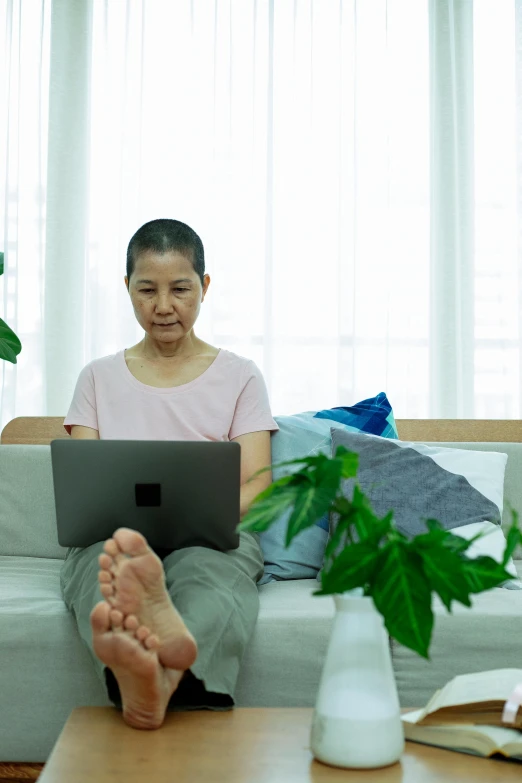 a woman sitting on a couch using a laptop, kuang hong, a bald, diagnostics, plants