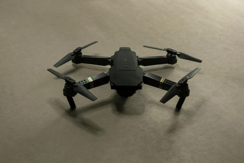 a small black drone sitting on top of a table, pexels contest winner, computer art, low quality footage, frontal pose, ground, jet - black skin
