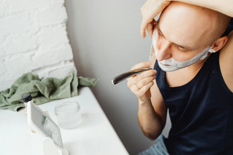 a man shaving his face with a razor, by Adam Marczyński, trending on pexels, happening, avatar image, short white beard, bo burnham, on a white table