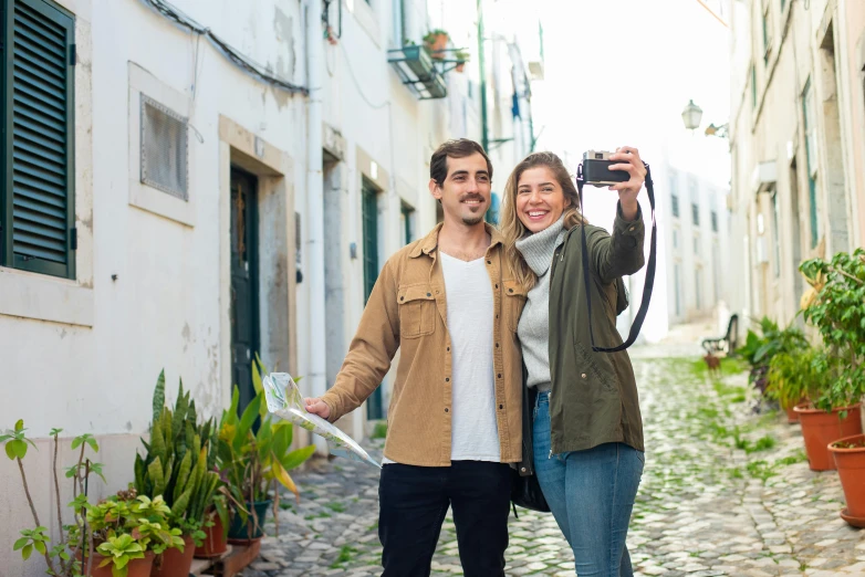 a man and woman taking a selfie in an alleyway, a picture, portugal, holding a dslr camera, avatar image, guide