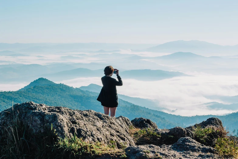 a person standing on top of a mountain taking a picture, girl clouds, profile image, multiple stories, candid photography