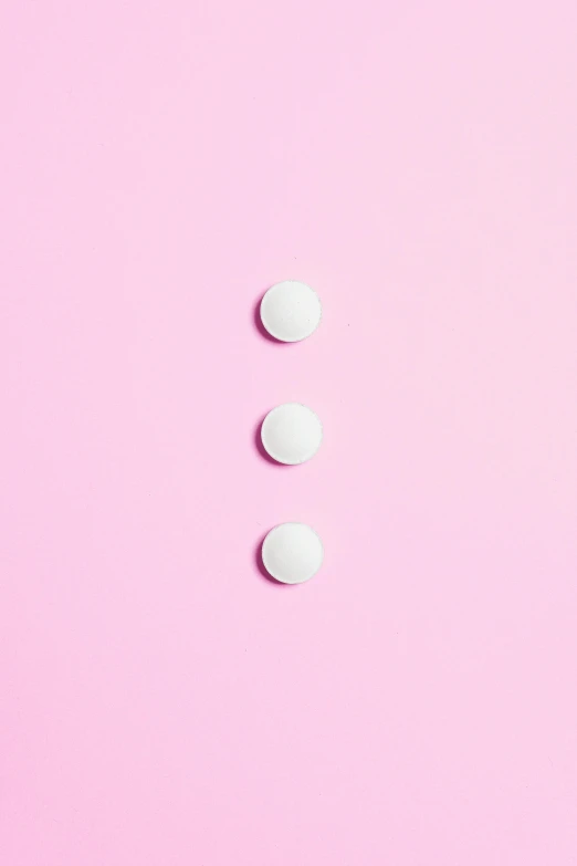 three white pills on a pink background, by Évariste Vital Luminais, trending on pexels, postminimalism, back - shot, panel, studs, top - down photograph