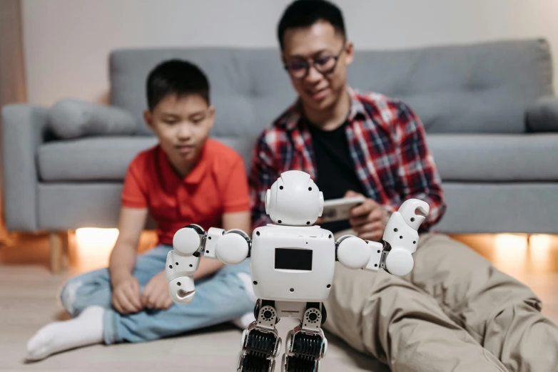 a man and a boy sitting on the floor playing with a robot, pexels contest winner, avatar image, asian male, parents watching, instagram photo