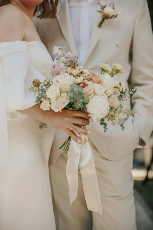 a man and a woman standing next to each other, by Sara Saftleven, pexels contest winner, romanticism, bouquet, beige and gold tones, zoomed in, wearing a white tuxedo