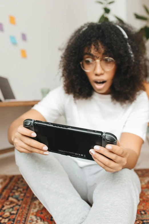 a woman sitting on the floor playing a video game, trending on pexels, happening, looking surprised, handheld, black teenage girl, close up to the screen
