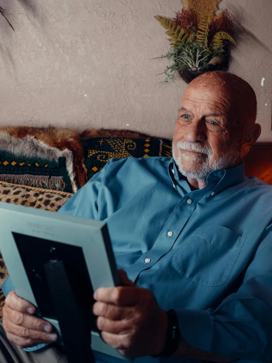 a man sitting on a couch reading a book, a portrait, pexels contest winner, mike ehrmantraut, home video footage, portrait of bedouin d&d, using a magical tablet