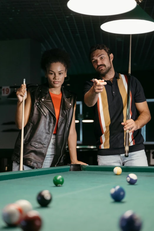 a man and a woman playing a game of pool, outlive streetwear collection, model is wearing techtical vest, thumbnail, tessa thompson