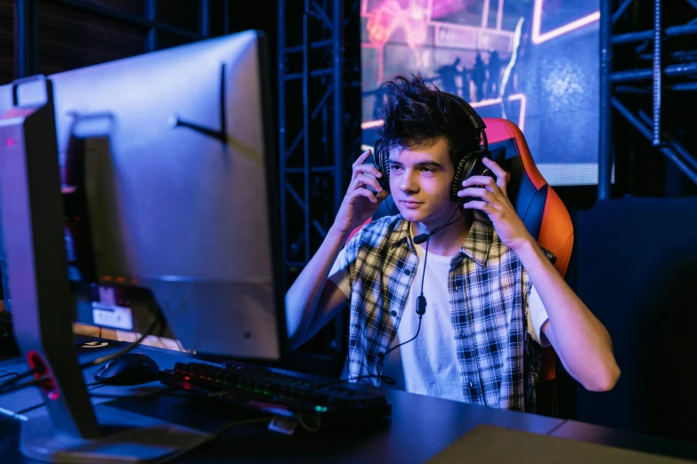 a young man wearing headphones sitting in front of a computer, gamer themed, performing, official screenshot, no watermarks