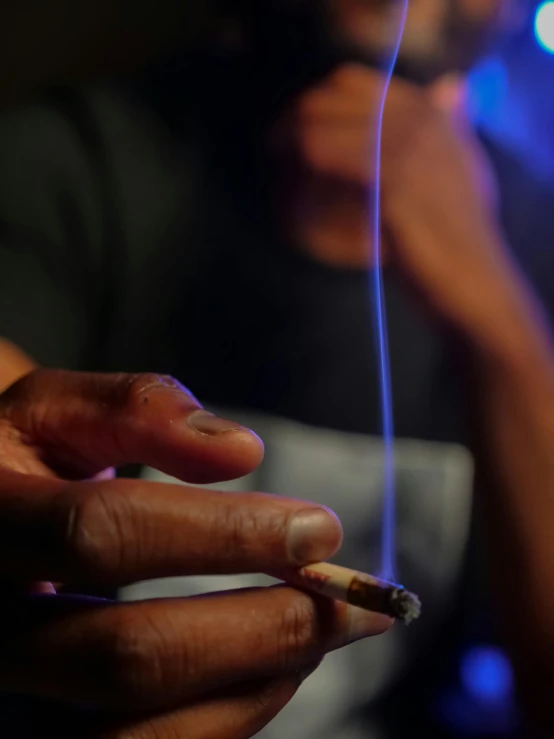 a close up of a person holding a cigarette, light show, sitting down, pot leaf, nightlife