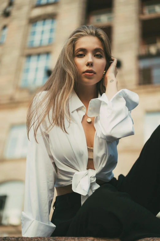 a woman sitting on a ledge talking on a cell phone, by Sebastian Vrancx, trending on pexels, renaissance, button up shirt, white bra, bows, sleek flowing shapes