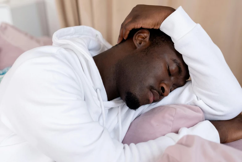 a man laying in bed with his eyes closed, trending on pexels, renaissance, black head, tall forehead, african man, tinnitus