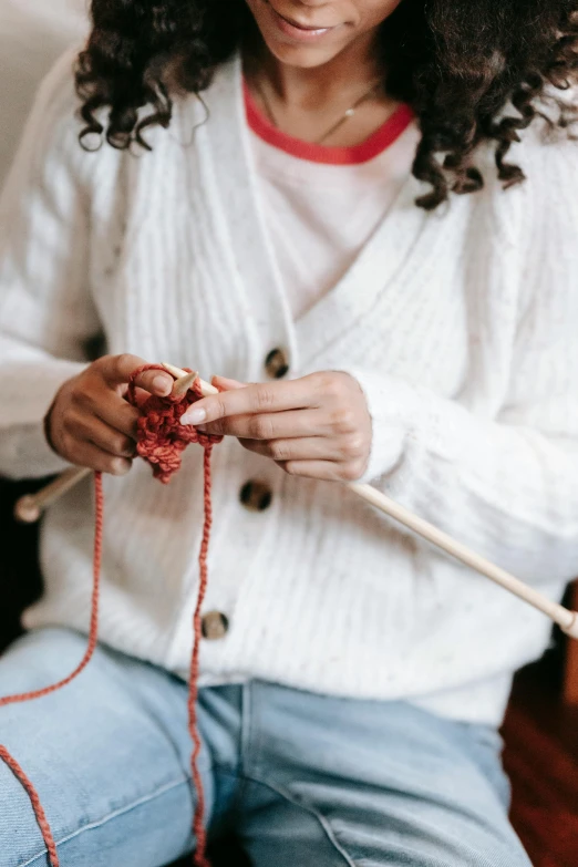 a woman sitting on a couch knitting a piece of yarn, trending on pexels, wearing a white button up shirt, reds), holding a wooden staff, avatar image