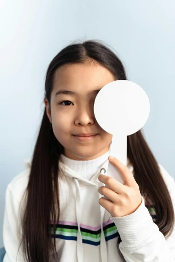 a girl holding a mirror in front of her face, eye patch over left eye, wearing lab coat, south east asian with round face, for kids