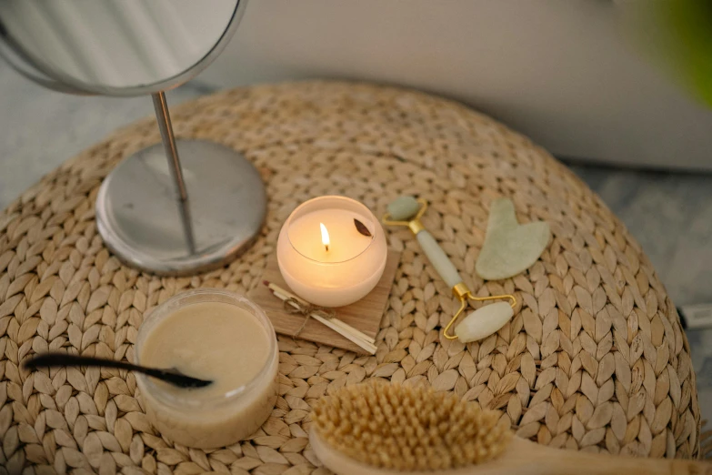 a candle sitting on top of a table next to a mirror, detailed product image, spoon placed, flatlay, ivory